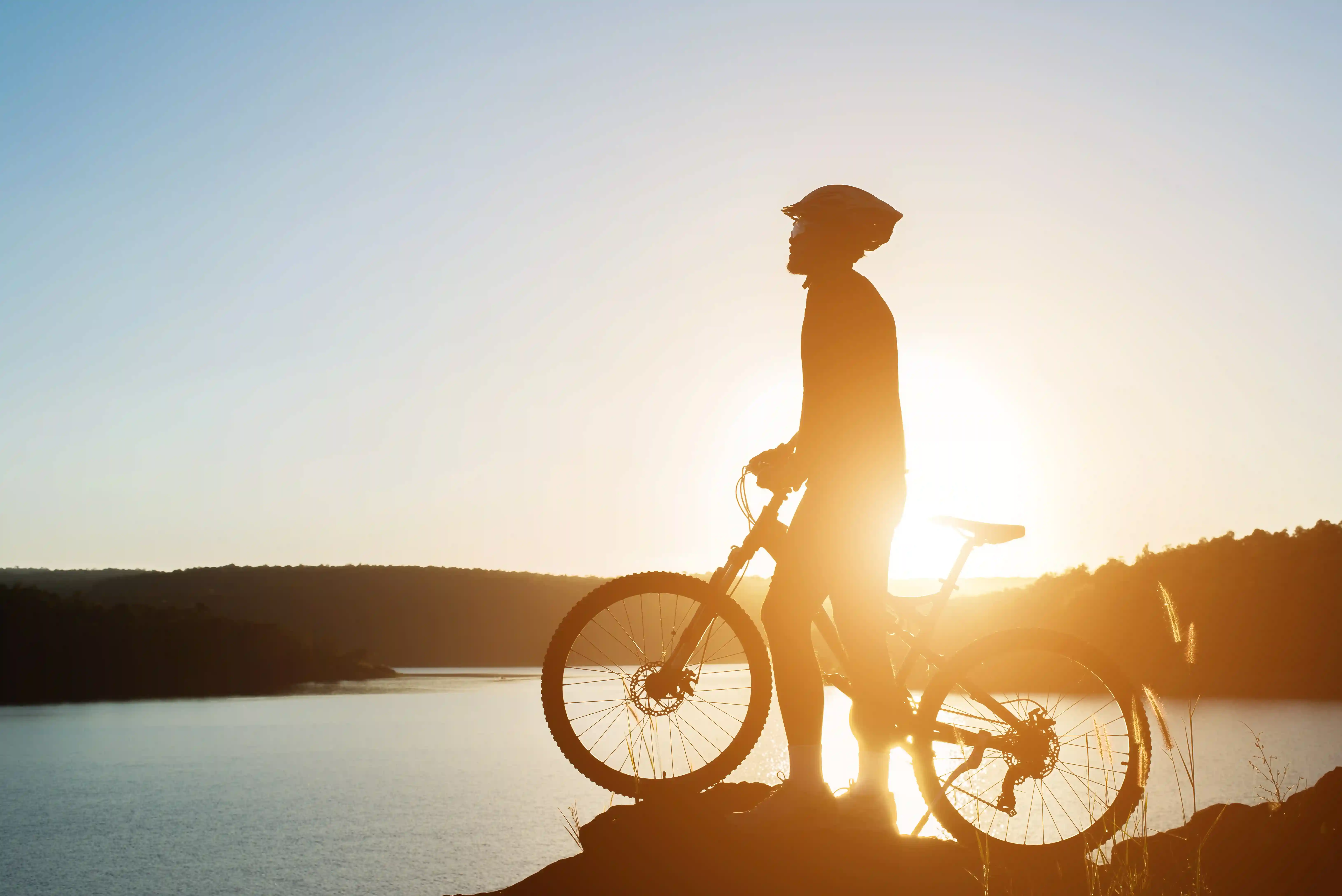 Cyclist overlooking Italian valley at sunset